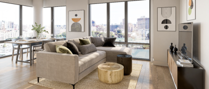 living room with brown sofa, natural colors, wood floors, & large windows overlooking water